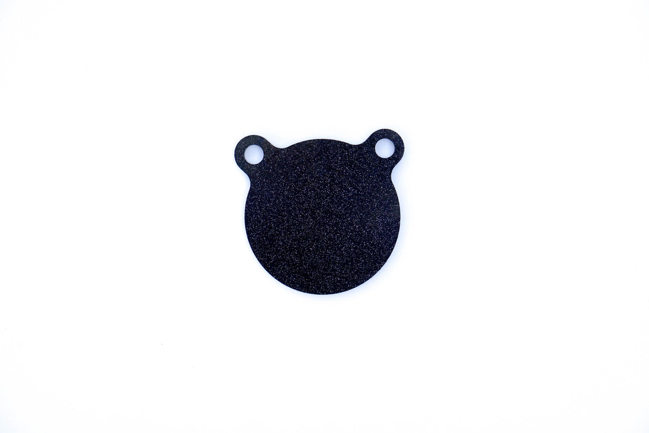 The Yankee Thunder AR500 4-Inch Gong Target (1/4" Thick) - SMALL is a black, circular object featuring two small loops at the top, resembling a bear's head with ears, crafted from durable AR500 steel. Its unique design makes it seamlessly compatible with the Hang n Hook system and is presented on a white background.